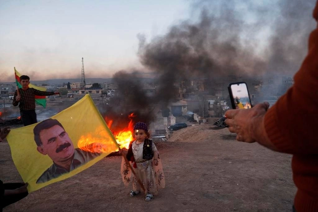 A child holds a flag bearing the image of Kurdish leader Abdullah Ocalan during Nowruz celebrations in Amuda, Hasakah region, Syria.