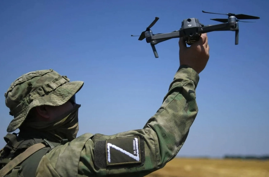 Russian soldier with a Z symbol on his sleeve launching a Chinese DJI Mavic quadcopter drone.